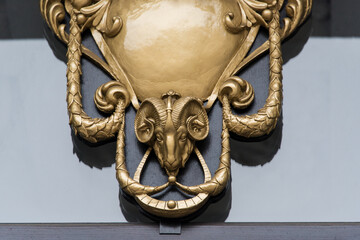 Metal goat head on the facade of the building. Animal art, ram head face eclectic antique reflief....