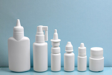 A diverse set of white plastic containers for pharmacy drugs, lined up in order of size in height. On a light blue background.