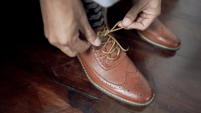 Groom's Hands Tying Lace Of Brown Leather Shoe. Man Preparing For Wedding Day. Close Up