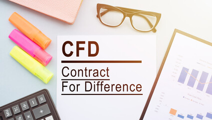 The text CFD - Contract For Difference, on office desk with calculator, markers, glasses and...