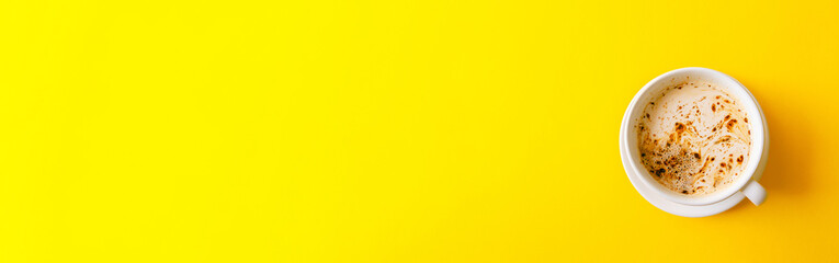A cup of black coffee with milk and foam on yellow background. Top view. Flat lay.