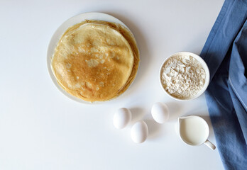 A lot of pancakes are stacked on a white plate. Thin pancakes with a crispy crust. Pancake day.