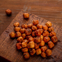 A handful of nuts are scattered on a board on a wooden table.