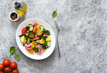 Mix salad with peppers, tomatoes and cucumber in a plate on a concrete background. Ala Greek salad.