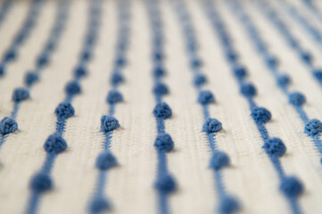 Fototapeta premium Crochet product from multicolored threads. Handmade backdrop. Fragment of a plaid of blue and ivory tone. Striped, geometric pattern.