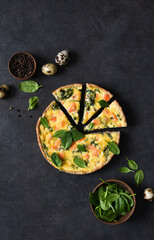 Tart with salmon and spinach, cheese on a black concrete background. Quiche with fish.