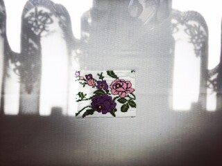 The shade of the curtain on the floral-patterned tablecloth. Background and texture.