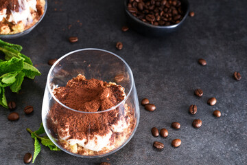 Dessert tiramisu in a glass on a dark concrete background.