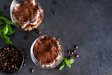 Dessert tiramisu in a glass on a dark concrete background.
