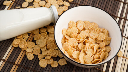 Healthy cornflakes and milk on a bamboo napkin.