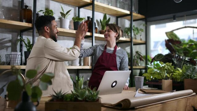 Shop assistants with laptop working in indoor potted plant store, small business concept.