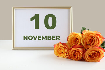Fototapeta premium day of the month 10 November calendar photo frame and yellow rose on a white table
