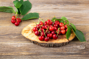 bunch of ripe sweet cherries with green leaves on wooden background