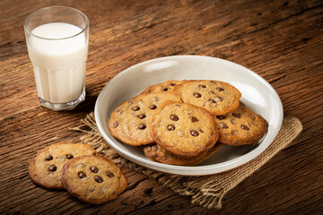 Delicious chocolate cookies with glass of milk on wooden table.