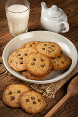 Delicious chocolate cookies with glass of milk on wooden table.