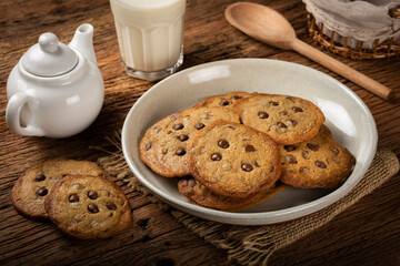 Delicious chocolate cookies with glass of milk on wooden table.