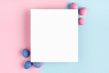 Minimal Easter flat lay composition from Easter eggs and blank white canvas on pastel blue-pink background. Top view, copy space for text