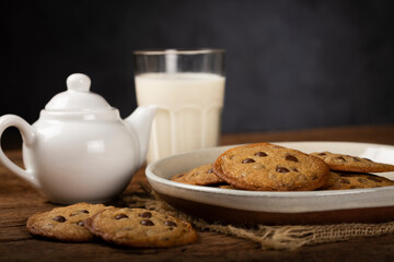 Delicious chocolate cookies with glass of milk on wooden table.