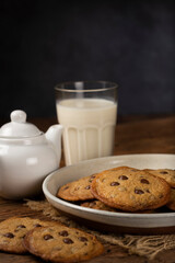 Delicious chocolate cookies with glass of milk on wooden table.