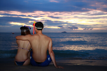 Couple in love hug together and watching sunset together on beach,couple sitting on beach rear view