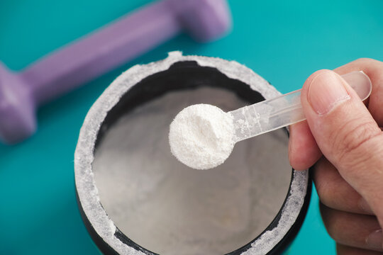 AAKG supplement. Man holding a scoop of AAKG powder in his hand