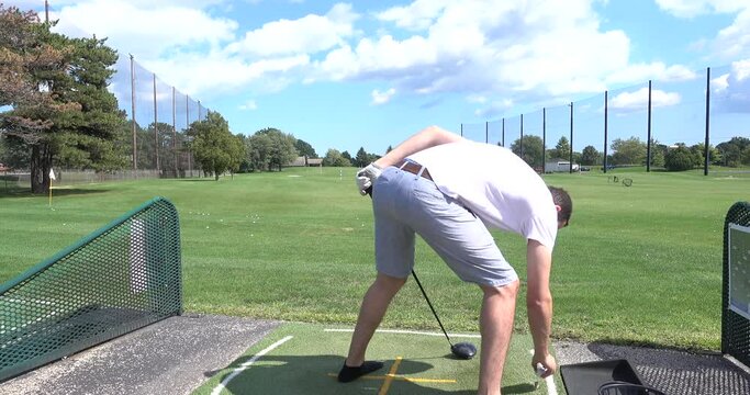 Young man hitting golf balls at a driving range