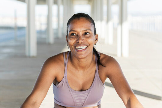 Side view of young ethnic sportswoman in active wear working out on pavement