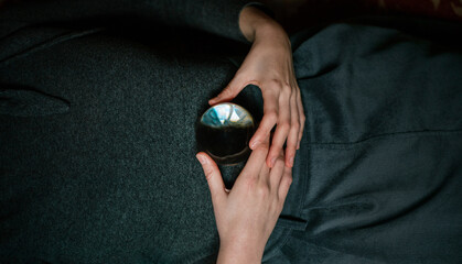 Close up view of anonymous relaxed female lying on carpet holding transparent crystal ball with hands