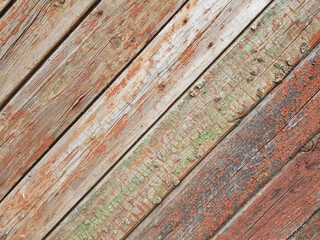 textured background of old time-worn wooden planks, set at an angle of 45 degrees, from a mixture of red, white and brown colors, siding of a wood panel of an old house, close-up, no people, patern. 