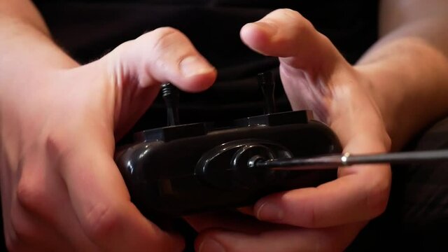 Close-up of a man's hands holding remote control and operating a radio-controlled car
