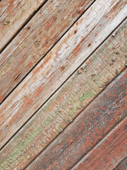 textured background of old time-worn wooden planks, set at an angle of 45 degrees, from a mixture of red, white and brown colors, siding of a wood panel of an old house, close-up, no people, patern. 