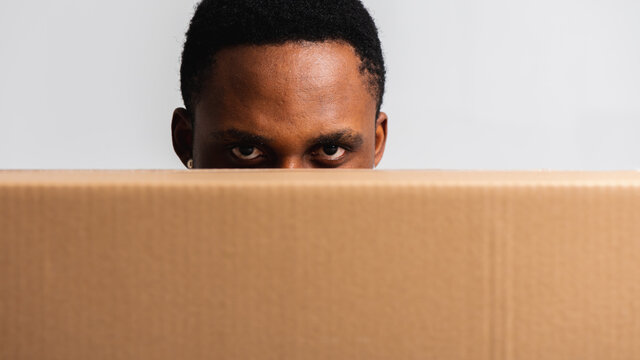 Delivery Man Holding A White T-shirt And Blue Pants With A Box In His Hands. Isolated On A White Background. Concept Of Delivery, Mail, Shipment, Loader, Courier. Box Close Up