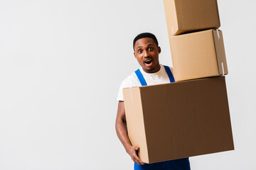 A delivery man wearing a white T-shirt and blue pants holds boxes in his hands. Isolated on a white...