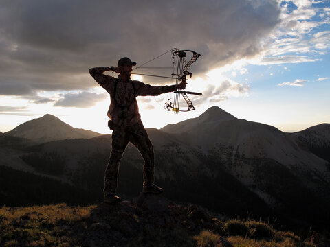 modern bowhunter silhouette with mountains and sky