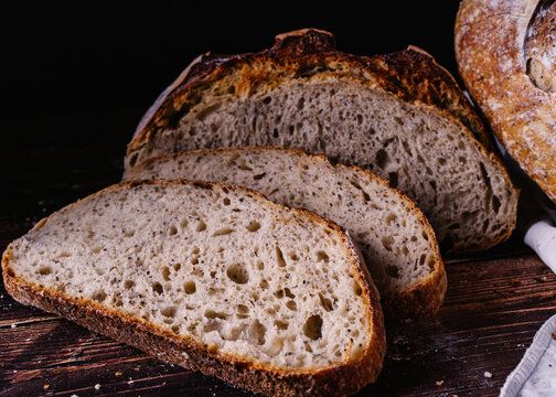 Slices of baked bread placed on wooden table in kitchen