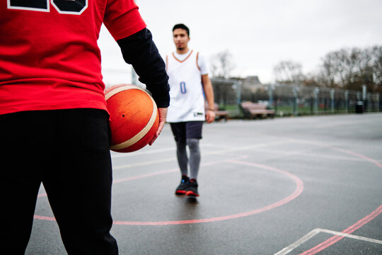 Cropped image of male friends playing basketball at the court. Blurred background. Copy space.