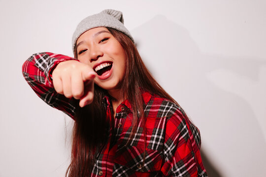 Close-up portrait of cheerful Asian young woman pointing at camera with finger