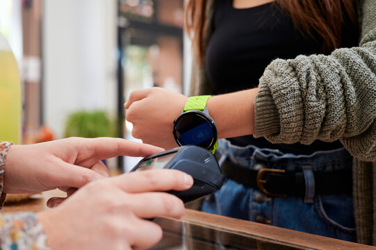 Crop faceless female client with gadget for contactless payment on wireless terminal in shop
