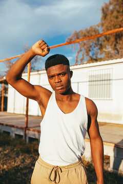 Masculine ethnic male protester in undershirt standing with raised arm in countryside