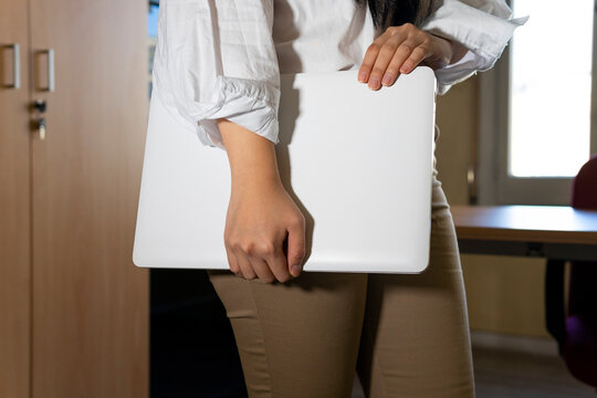 Crop anonymous female executive in smart casual wear with convenient portable computer against table in building