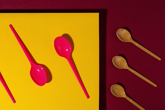 Overhead view of bright red and brown eco friendly spoons near yellow carton sheet
