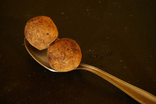 Tasty Several Chocolate Truffles with cocoa powder in the spoon on black slate board