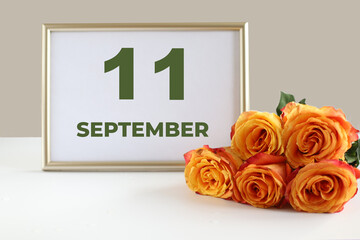 day of the month 11 September calendar photo frame and yellow rose on a white table