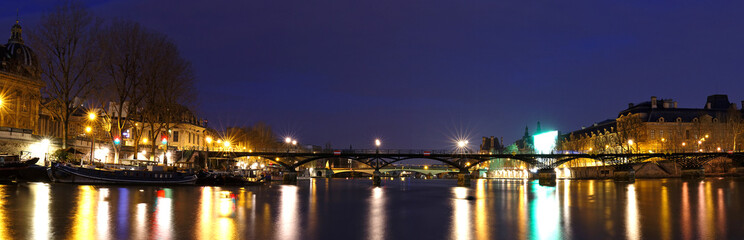 Obraz premium The panoramic night view of Seine river during the night with famous bridge Pont des Arts, Paris, France.