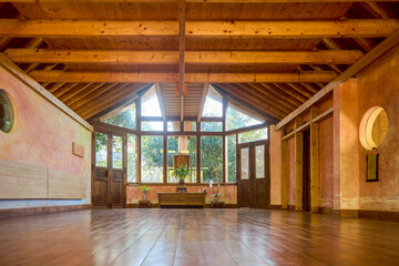Interior of spacious meditation hall in house with potted plants and parquet in daytime