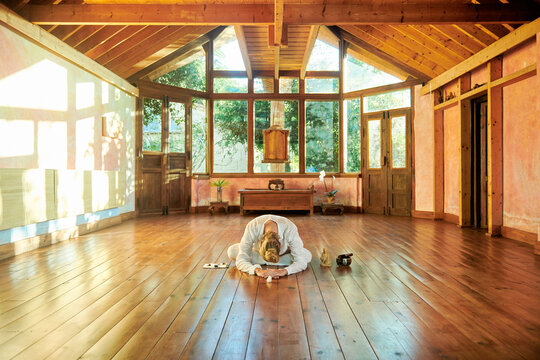 Anonymous flexible male sitting in Baddha Konasana pose while practicing yoga on floor in sunlight
