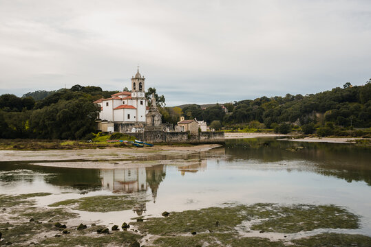 Picturesque scenery of white Parish of Our Lady of Sorrows on tranquil shore on overcast weather in Asturias Spain