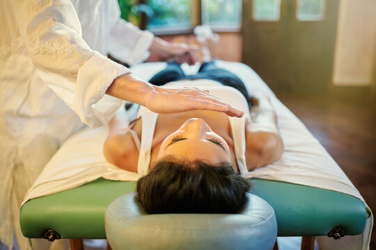Crop male practitioner healing female patient with palm technique for recovering soul and body