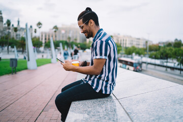 Fototapeta premium Young ethnic man messaging on smartphone on street