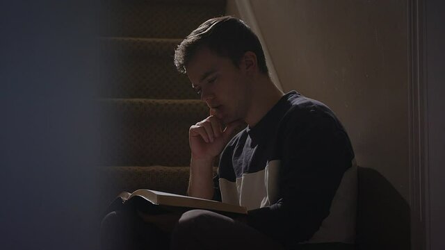 young man reading a bile on staircase